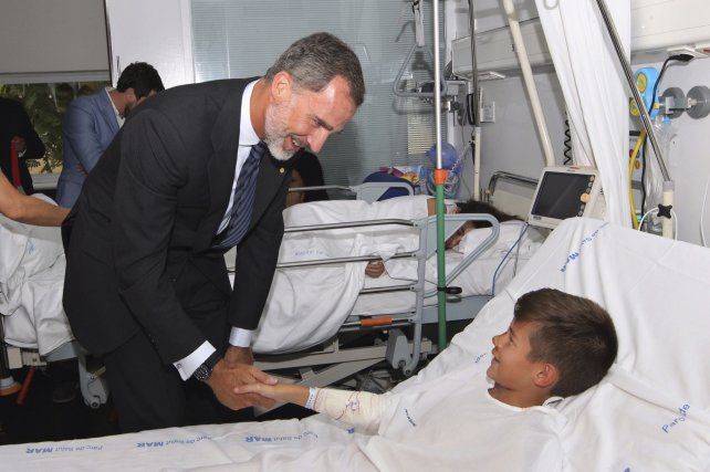 El rey Felipe saluda a uno de los niños que sufrieron heridas en el atentado. 
